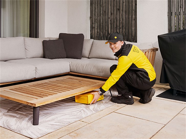 Zusteller*in hinterlegt Paket auf Terrasse